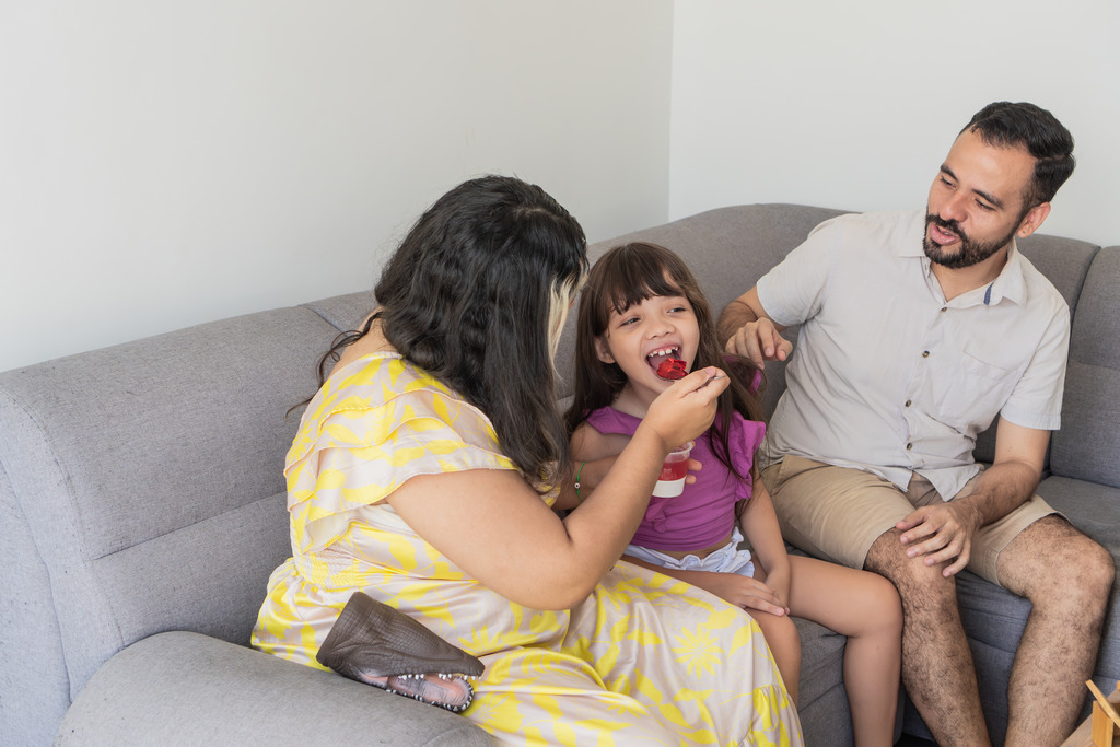 Mother Feeding Daughter a Snack While Father Watches