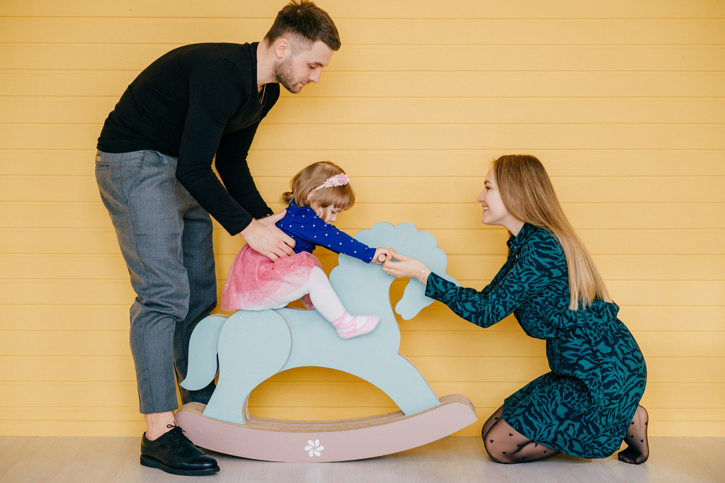 Cheerful young family with one female child having fun together and smiling