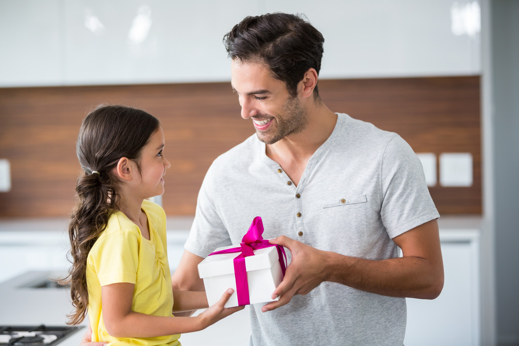 Smiling father giving gift box to daughter