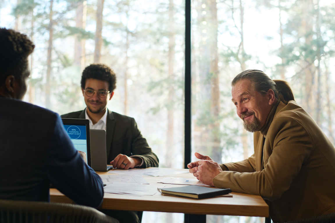 Smiling mature chief executive officer talking to young male subordinate